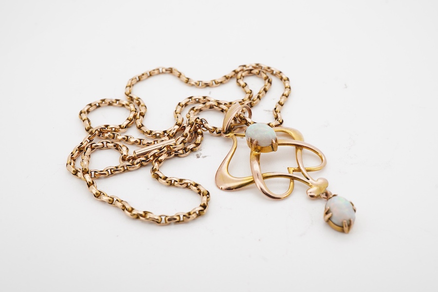An Art Nouveau gold and opal pendant and chain, early 20th century, the pendant of sinuous design, set with two cabochon opals, to a gold belcher link chain necklace, chain length 45cm, stamped 15ct, pendant 4.7cm, stamp